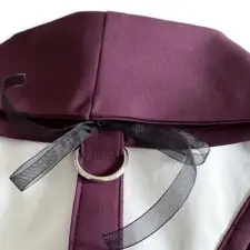 Detalle del anillo metálico y la cinta portaalianzas de organza en la parte trasera del arnés burdeos